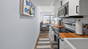 A modern kitchen with white cabinets, a wooden countertop, and a stainless steel oven.