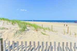 A sandy beach with a wooden fence in the foreground and a lifeguard tower in the distance. - Ocean Block 1 Bedroom-Sleeps6-Pool (Ocean City)