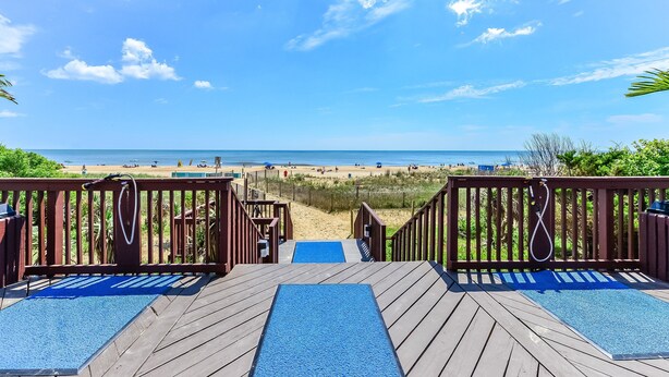 A wooden deck with a pool, leading to a beach with people and a clear sky. - Oceanfront 2 Bed/2Bath,IndoorPool,Game Room (Ocean City)