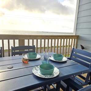 A table with green bowls and glasses, a chair, and a view of the water and pier. - Dancing Dolphin-Waterfront! Hot Tub, Arcade, Pool, Gas Grill-Walk to Pier & Pubs (Fulton)