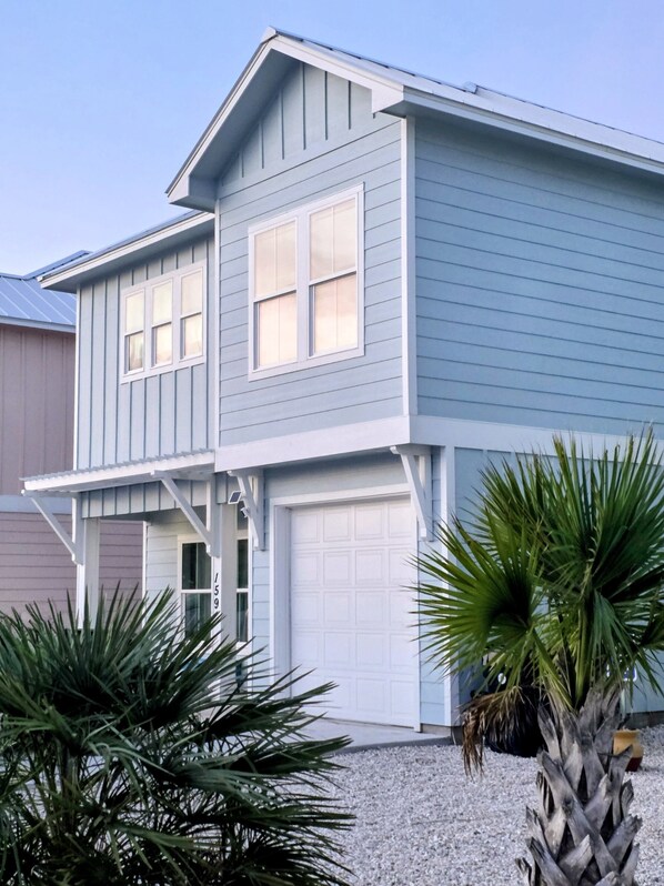 A two-story house with a garage, a covered porch, and a gravel driveway.