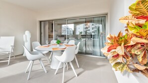 A modern dining area with a round table, white chairs, and a glass partition.