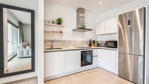 A modern kitchen with white cabinetry, stainless steel appliances, and a built-in oven.