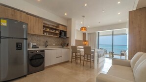 A modern kitchen with a built-in washing machine, wooden cabinets, and a dining area with a view of the sea. - Seaside Serenity and Style (Cartagena de Indias)