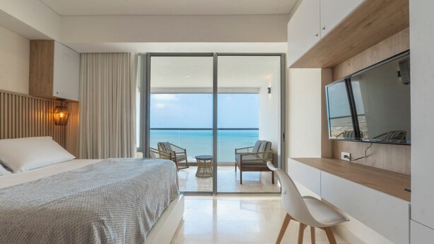 A modern hotel room with a bed, a desk, a chair, and a TV. - Seaside Serenity and Style (Cartagena de Indias)