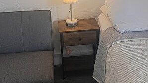 Ein Schlafzimmer mit einem Bett, einem Nachttisch mit Lampe und einem Sessel.
