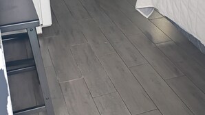 Ein Schlafzimmer mit einem Bett, einem Schreibtisch, einem Stuhl, einer Tür zu einem Badezimmer und einem Mülleimer.