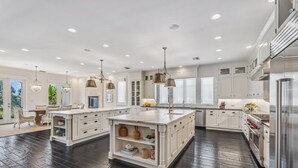 Une cuisine spacieuse avec des meubles blancs, un grand îlot central et un plancher en bois foncé.