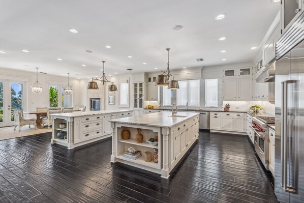 Una cocina amplia con armarios blancos, una isla grande y piso de madera oscura.