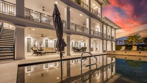 Un hôtel à plusieurs étages doté d’une piscine, d’un espace extérieur aménagé et offrant une vue sur le coucher de soleil.