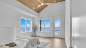 A spacious bedroom with a large bed, a ceiling fan, and a view of the ocean through large windows. - Oceanfront Luxury | 4BR w/ Elevator sleeps 12 (North Topsail Beach)