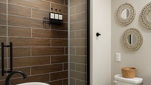 Een badkamer met een douchecabine van glas, een wit wastafelmeubel en een toilet.