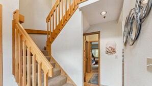 A staircase with wooden railings leading to a bedroom with a bed and a wall-mounted artwork. - Lakeside Comfort  • Walk to Lake Dillon • Minutes to Ski Resorts (Frisco)