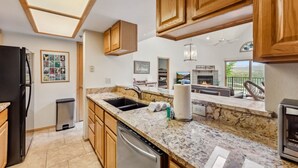 A modern kitchen with granite countertops, wooden cabinets, a built-in dishwasher, and a large window overlooking a scenic landscape. - Lakeside Comfort  • Walk to Lake Dillon • Minutes to Ski Resorts (Frisco)