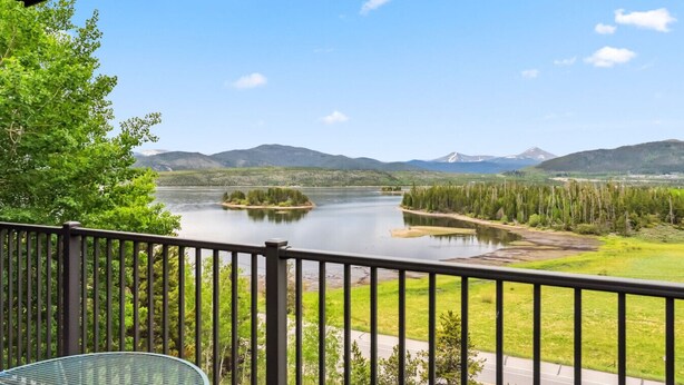 A balcony with a view of a lake, surrounded by greenery and mountains. - Lakeside Comfort  • Walk to Lake Dillon • Minutes to Ski Resorts (Frisco)