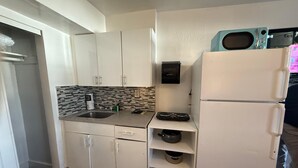 Uma cozinha compacta com armários brancos, micro-ondas, fogão e pia.