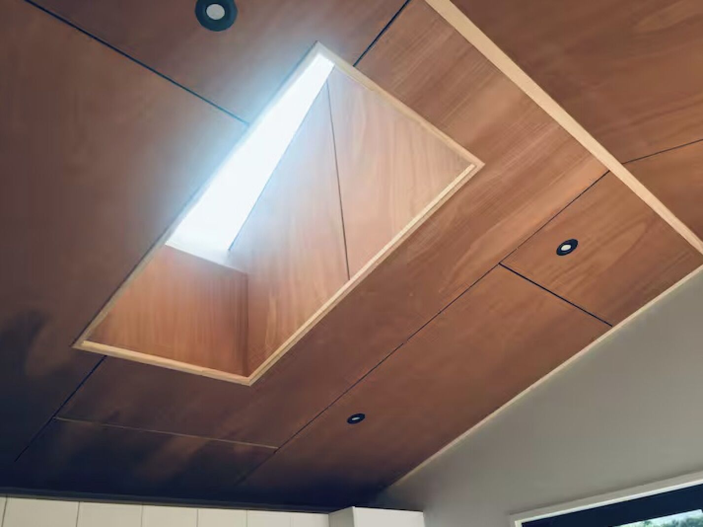 Un plafond doté d’un luminaire rectangulaire et d’un éclairage encastré.