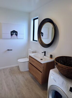 A modern bathroom with a toilet, sink, and washing machine. - Unique and modern self contained unit with total privacy and amazing views. (Queenstown)