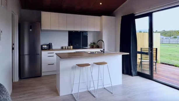 A modern kitchen with a central island, stainless steel appliances, and a large window offering a view of the outdoors.