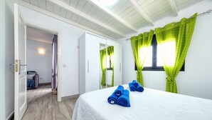 Une chambre d’hôtel avec un grand lit, des rideaux verts et une salle de bain visible au fond.