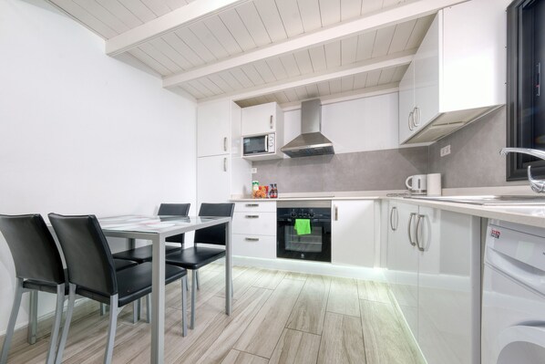 Una cocina moderna con armarios blancos, microondas integrado y campana extractora de acero inoxidable.