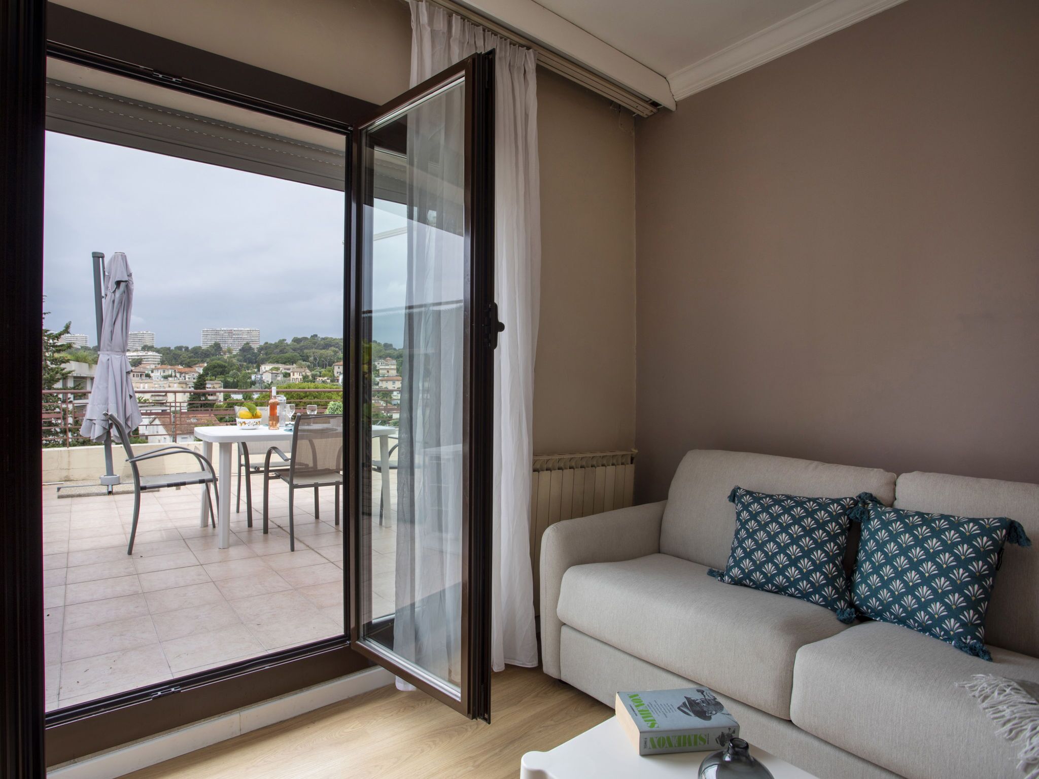 A living room with a sofa, a coffee table, and a view of a balcony with outdoor furniture.