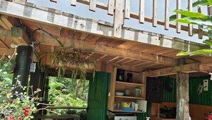 A rustic outdoor kitchen with a wooden table, a sink, and a refrigerator.