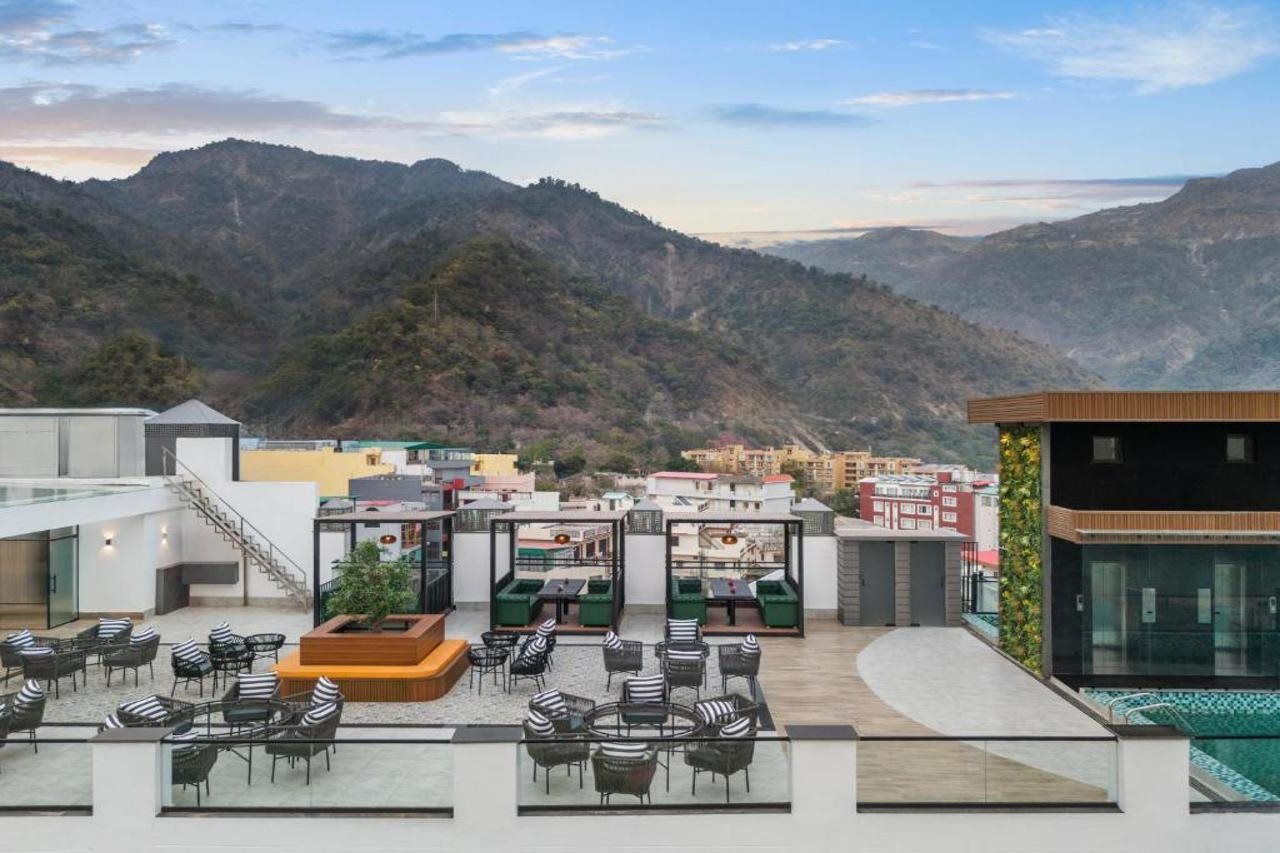 A rooftop terrace with outdoor seating and a pool, overlooking a mountainous landscape.
