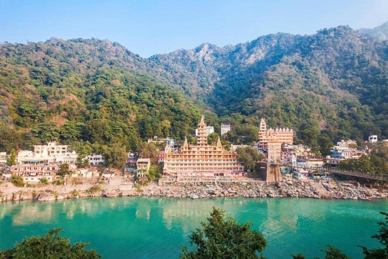 A riverside view with a prominent temple complex and surrounding buildings.