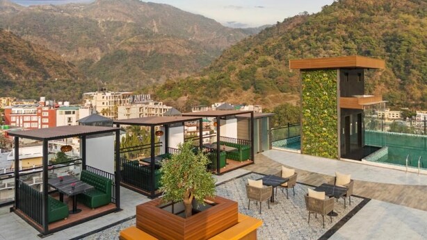 A rooftop terrace with outdoor seating, a small garden, and a view of a mountainous landscape. - Zana By The Ganges, Rishikesh (Narendranagar)