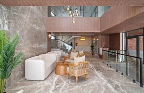 A spacious lobby with a marble floor, a white sofa set, a wooden chair, and a staircase in the background. - Zana By The Ganges, Rishikesh (Narendranagar)