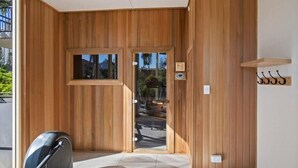 A modern interior with wooden paneling, a large sliding glass door, and a small seating area with a chair.