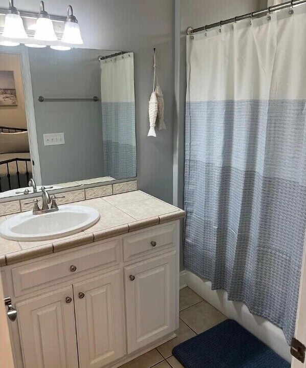A bathroom with a white sink, a mirror, a towel rack, and a shower curtain.