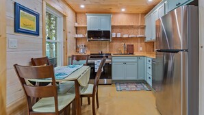 A compact kitchen with wooden cabinetry, a stainless steel refrigerator, and a dining table with chairs.