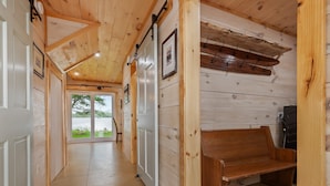 A wooden interior hallway with a bench, wooden walls, and a door leading outside.