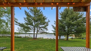 A covered patio with a view of a lake and trees.