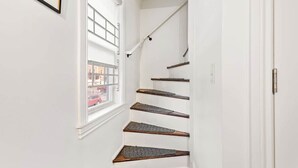 A narrow stairway with wooden steps and a white wall.