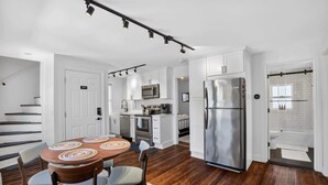 A modern kitchen with white cabinets, stainless steel appliances, and a dining area with a wooden table and chairs.