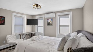 A bedroom with a bed, a desk, a chair, and a TV.