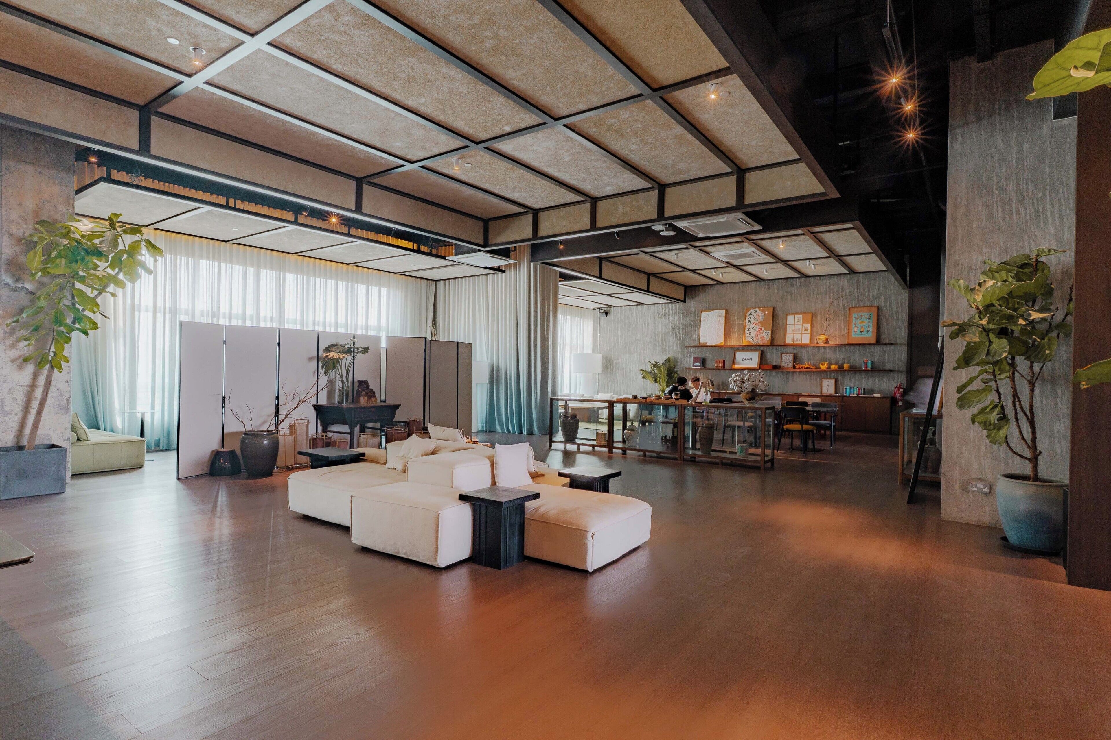 A spacious living area with a large sofa set, a dining table, and a kitchen area in the background.