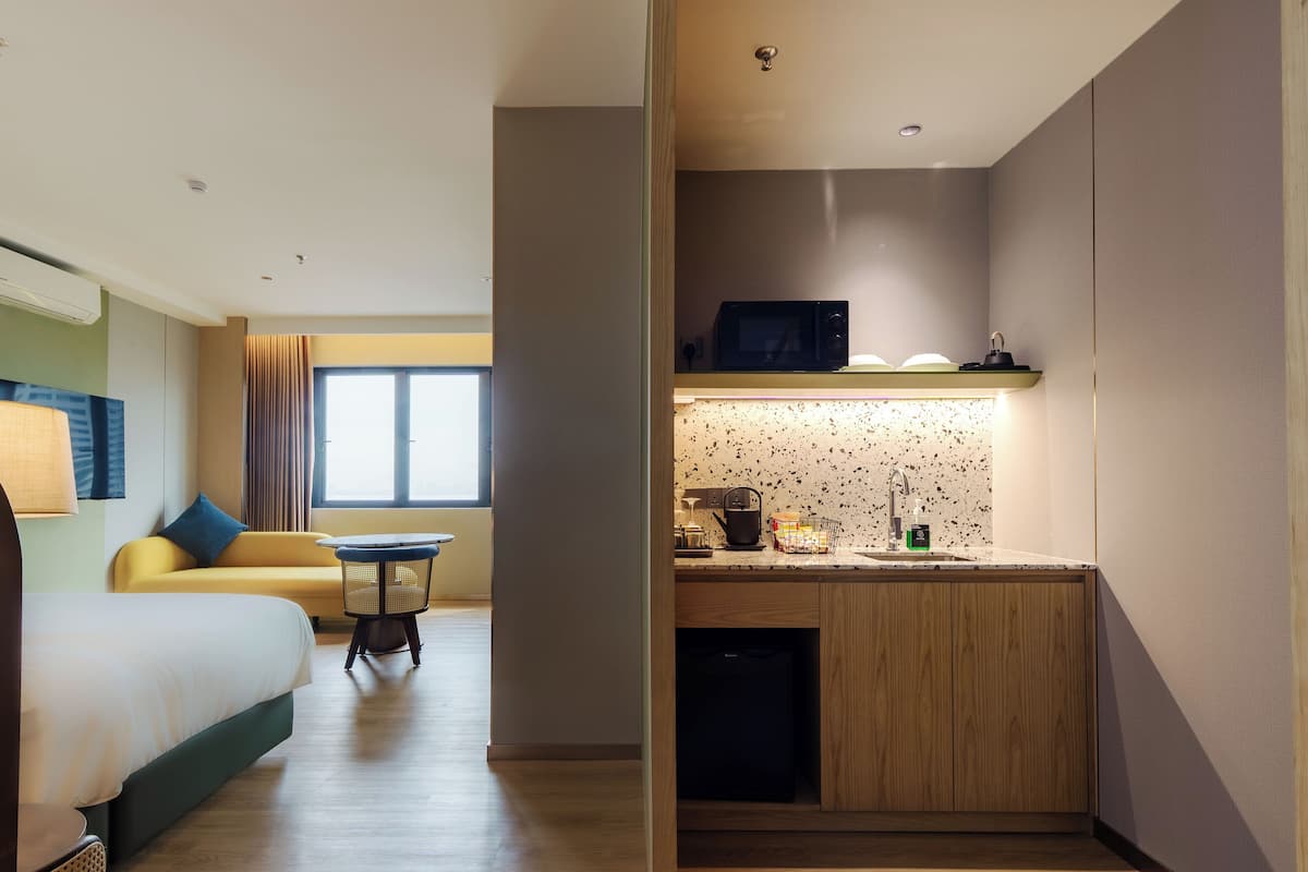 Une chambre d’hôtel de taille réduite, comprenant un lit, une petite table à manger, un four à micro-ondes et une kitchenette.