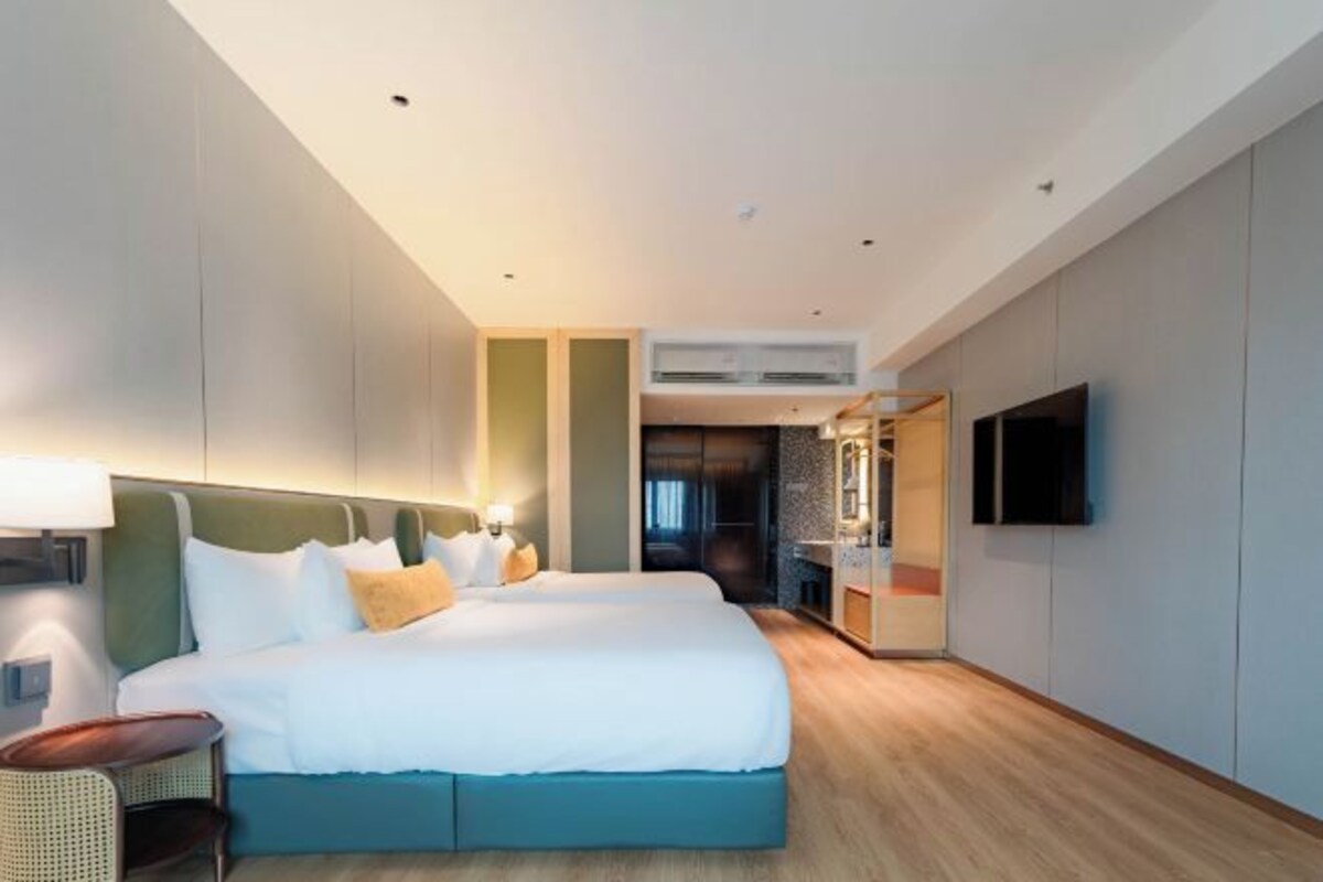 Une chambre d’hôtel moderne avec un grand lit, une télévision et une salle de bain équipée d’un miroir et d’un lavabo.