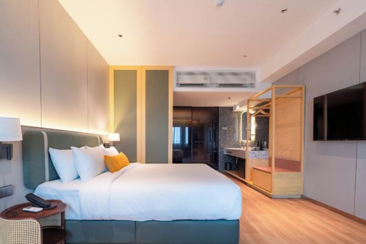 Une chambre d’hôtel moderne avec un grand lit, une télévision, une petite table et une armoire.