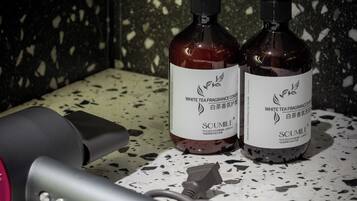 Two bottles of white tea fragrance conditioner and a hairdryer on a speckled countertop.