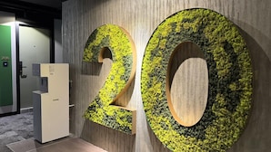 A wall with large numbers '20' made of a textured material, possibly moss, and a water dispenser to the left. - Shō Hotel Penang (George Town)