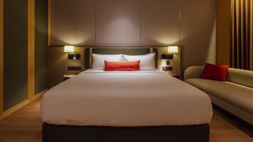 Una camera d'albergo moderna con un letto grande, un divano e due comodini con lampade.