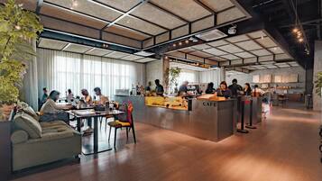 Una cafetería moderna con mostrador central, zona de estar y grandes ventanales.