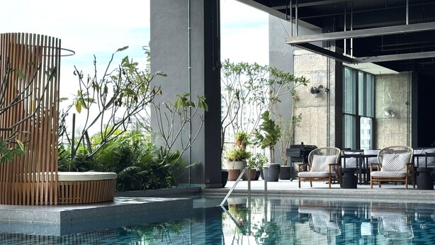 A modern indoor pool area with a clear pool, lounge chairs, and potted plants. - Shō Hotel Penang (George Town)