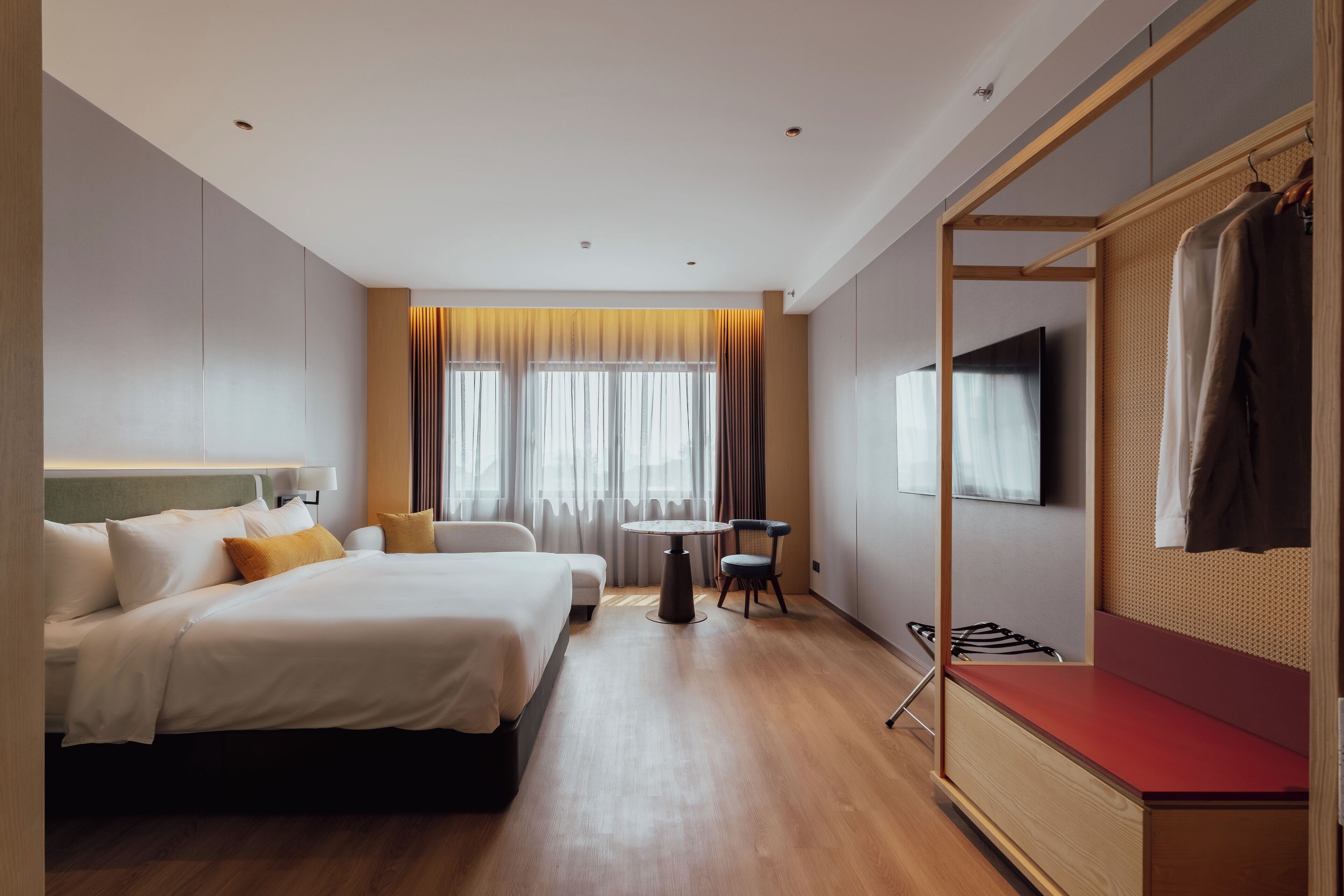 A hotel room with two beds, a small table, a TV, and a wardrobe.