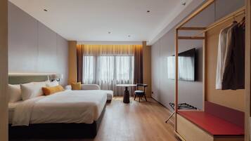 A hotel room with two beds, a small table, a TV, and a wardrobe.